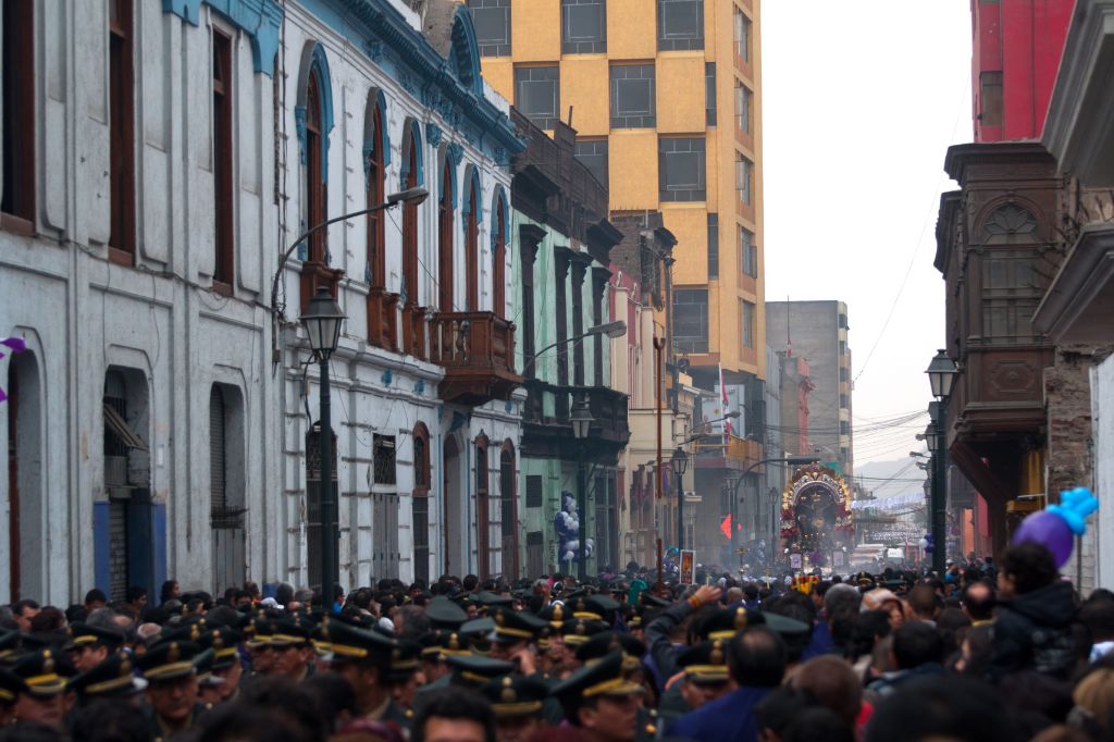 Una calle del centro histórico de Lima, con una multitud de personas acompañando al anda del Señor de los Milagros.